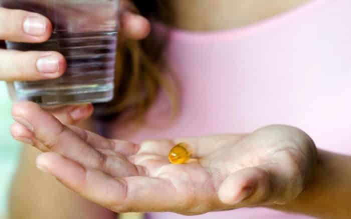 a woman about to take an omega 3 tablet as that is how to reverse hair loss from medication