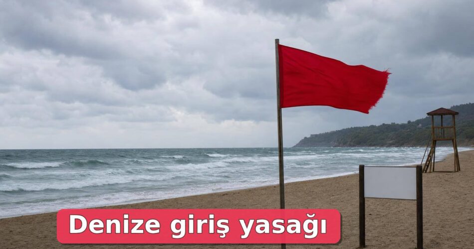Dalgalı deniz kıyısında kırmızı bayrak çekilmiş boş plaj.